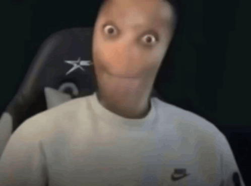 A Man With A Very Long Face Is Sitting In A Chair And Making A Surprised Face . GIF