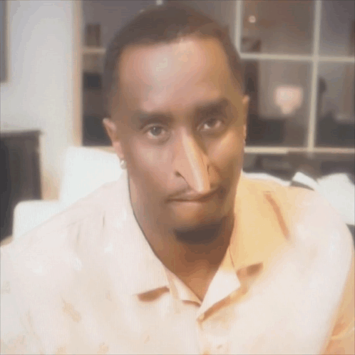 A Man With A Very Long Nose Is Wearing An Orange Shirt GIF