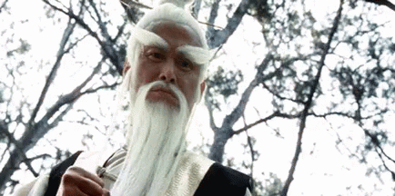 A Man With A White Beard And Mustache Is Standing In Front Of A Tree . GIF