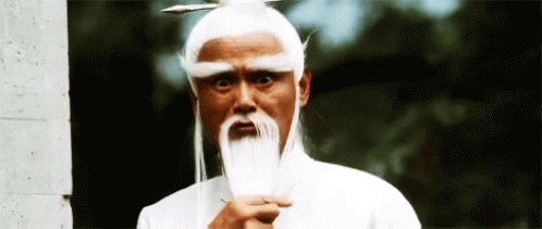 A Man With A White Wig And A Long Beard Is Holding A Sword . GIF