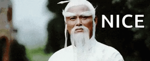 A Man With A White Wig And Beard Is Standing In Front Of A Sign That Says `` Nice '' . GIF