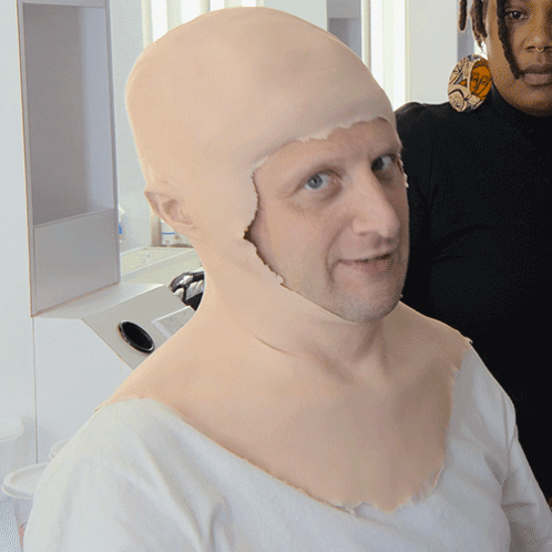 A Man With A Wig On His Head Is Standing Next To Another Man GIF