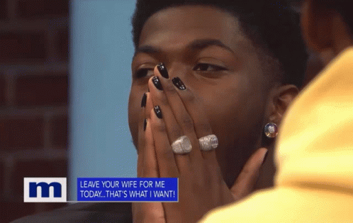 A Man With Black Nails And A Ring On His Finger Is Covering His Face In Front Of A M Sign GIF