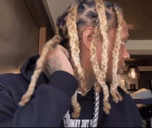 A Man With Blonde Dreadlocks Is Wearing A Black Hoodie That Says Lace Flying GIF