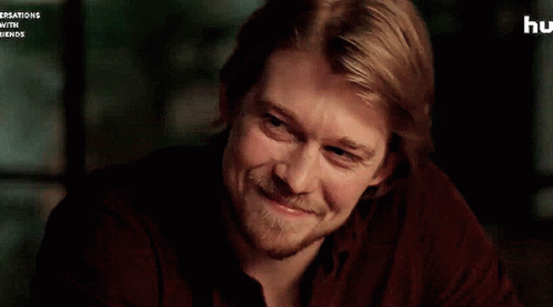 A Man With Blonde Hair And A Beard Is Smiling . GIF