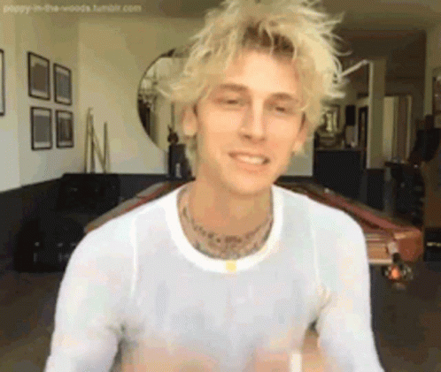 A Man With Blonde Hair And A White Shirt Is Sitting In A Living Room Next To A Pool Table . GIF