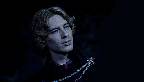 A Man With Blonde Hair And Blue Eyes Is Wearing A Black Coat GIF