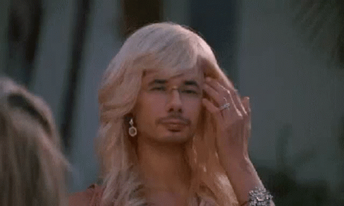 A Man With Blonde Hair And Glasses Is Wearing A Wig . GIF