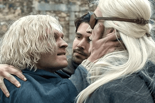 A Man With Blonde Hair Is Hugging Another Man And A Woman GIF
