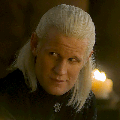 a man with blonde hair is wearing a black shirt and looking at the camera