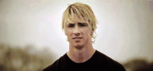 A Man With Blonde Hair Is Wearing A Black Shirt And Looking At The Camera GIF