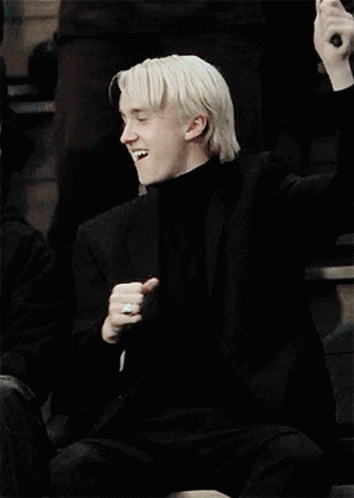 A Man With Blonde Hair Is Wearing A Black Turtleneck And A Black Jacket . GIF