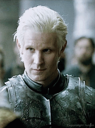 a man with blonde hair is wearing a knight 's armor and is looking at the camera