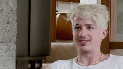 A Man With Blonde Hair Is Wearing A White Shirt And Gold Chain Around His Neck GIF