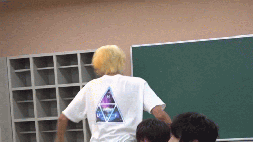 A Man With Blonde Hair Is Wearing A White Shirt With The Letter H On It GIF
