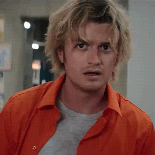 A Man With Blonde Hair Is Wearing An Orange Shirt And A Grey T-Shirt GIF