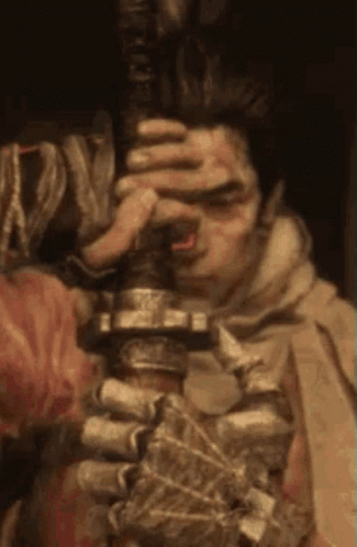 A Man With Blood On His Face Is Holding A Sword . GIF