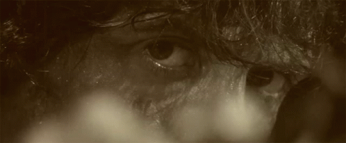 A Man With Blood On His Face Is Holding An Arrow GIF