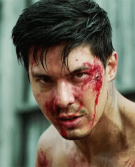 A Man With Blood On His Face Is Looking At The Camera GIF