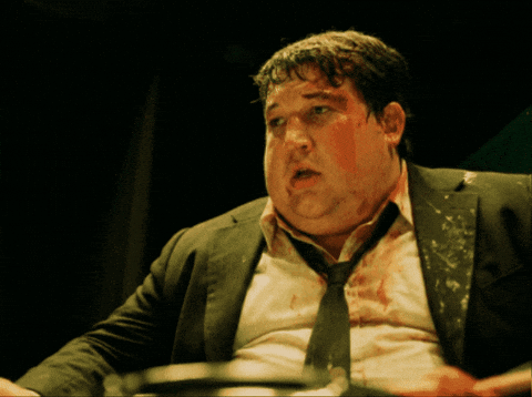 A Man With Blood On His Face Is Wearing A Black Suit And Tie GIF