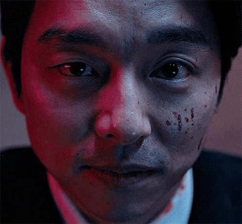 A Man With Blood On His Face Looks At The Camera GIF