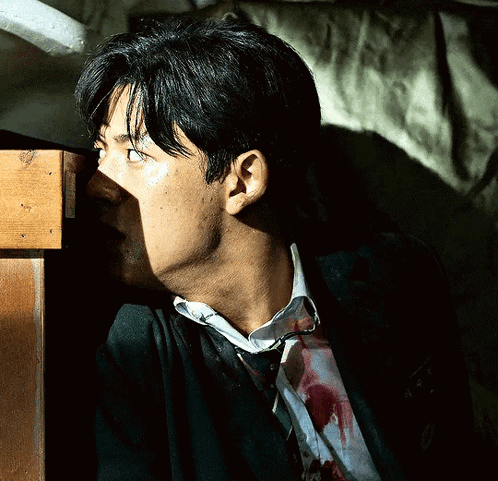 A Man With Blood On His Shirt Is Standing Next To A Table GIF