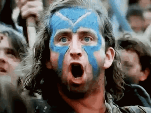A Man With Blue And White Paint On His Face Is Making A Surprised Face . GIF