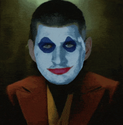 A Man With Blue Eyes And Red Lips Is Wearing A Red Jacket GIF