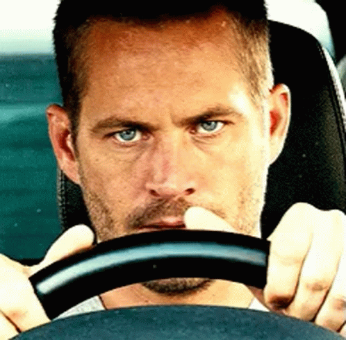 A Man With Blue Eyes Is Holding The Steering Wheel GIF