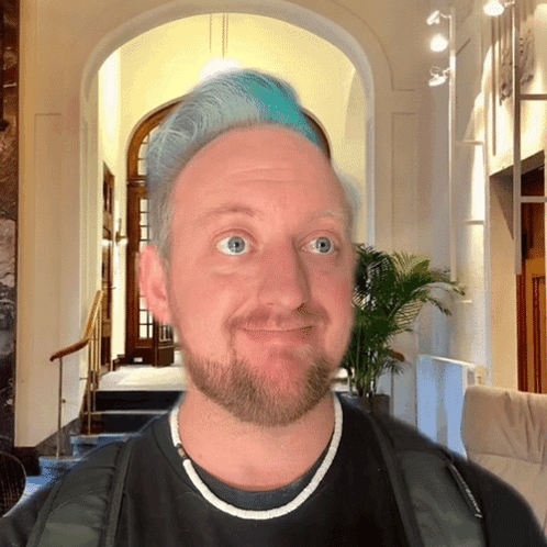 A Man With Blue Hair And A Beard Wears A Black Shirt GIF