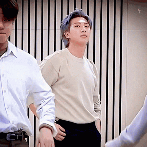 A Man With Blue Hair Is Standing Next To Another Man In A White Shirt And Black Pants . GIF