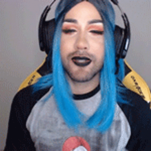 A Man With Blue Hair Is Wearing Headphones And A Wig While Sitting In A Chair . GIF
