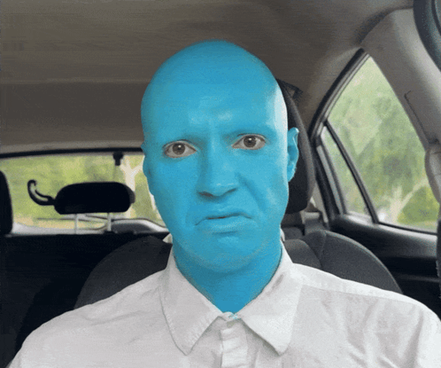 A Man With Blue Paint On His Face Is Sitting In The Driver 'S Seat Of A Car GIF