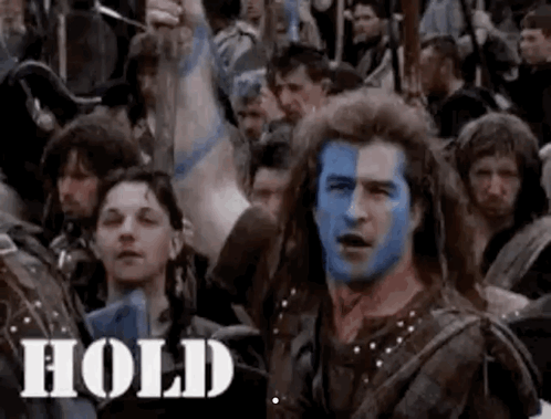 A Man With Blue Paint On His Face Is Surrounded By A Crowd Of People . GIF