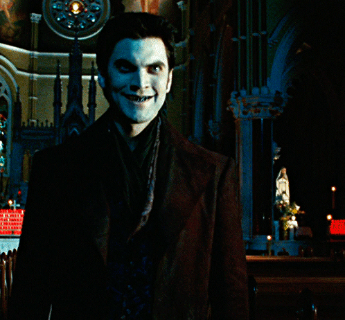 A Man With Blue Paint On His Face Stands In Front Of A Building GIF