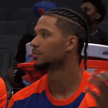 A Man With Braids On His Head Is Wearing A Blue And Orange Shirt GIF