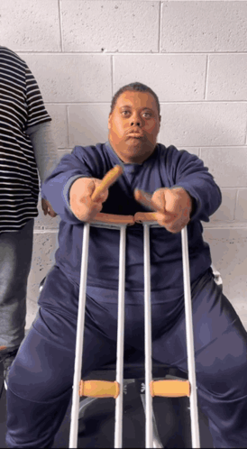 A Man With Crutches Is Holding A French Fry GIF