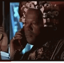 a man with curlers in his hair is talking on a phone