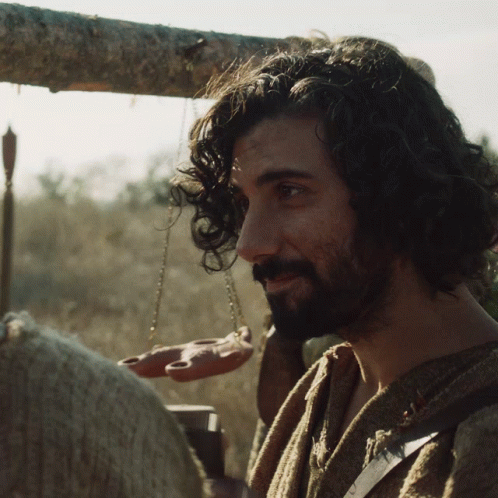 A Man With Curly Hair And A Beard Holds A Scale GIF