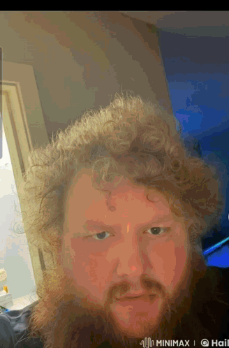 A Man With Curly Hair And A Beard Is Taking A Selfie In A Room GIF