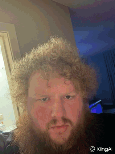 A Man With Curly Hair And A Beard Is Taking A Selfie With Klingai In The Corner GIF