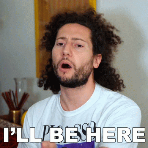 A Man With Curly Hair And A Beard Is Wearing A White Shirt That Says I 'Ll Be Here GIF