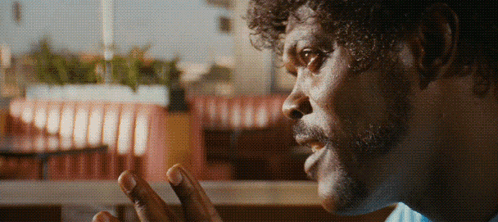 A Man With Curly Hair And A Beard Looks At Something GIF