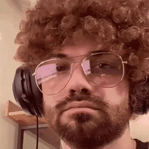 A Man With Curly Hair And A Beard Wearing Headphones And Glasses GIF