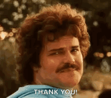 A Man With Curly Hair And A Mustache Is Giving A Thank You Gesture . GIF