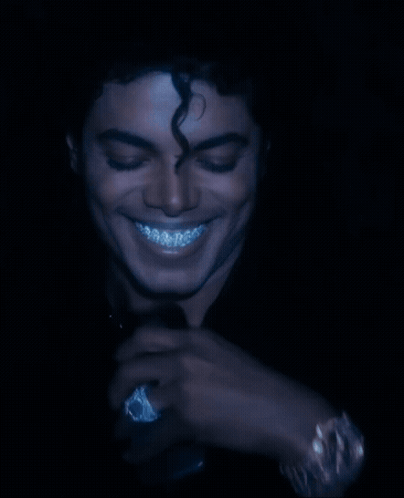 A Man With Curly Hair And Braces On His Teeth Is Smiling GIF