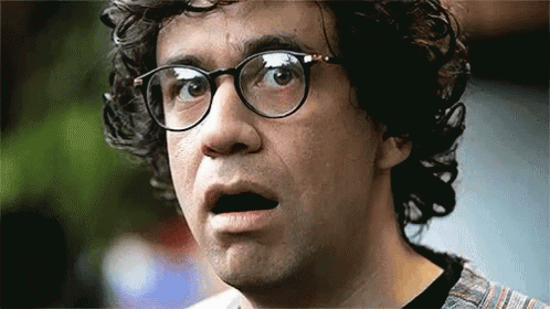 A Man With Curly Hair And Glasses Is Making A Funny Face . GIF