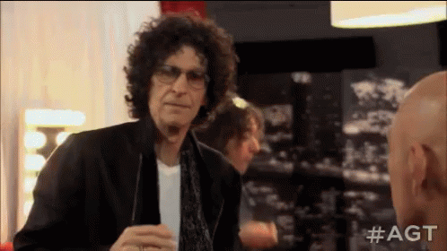 A Man With Curly Hair And Glasses Is Talking To Another Bald Man . GIF