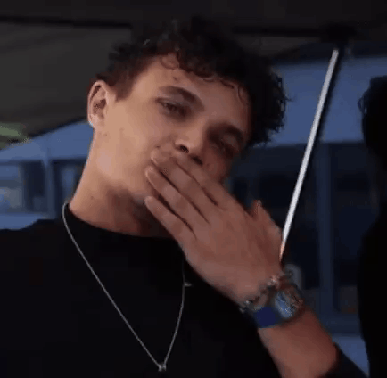 A Man With Curly Hair Is Covering His Mouth With His Hand . GIF