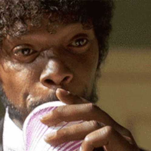 A Man With Curly Hair Is Drinking From A Pink Cup GIF